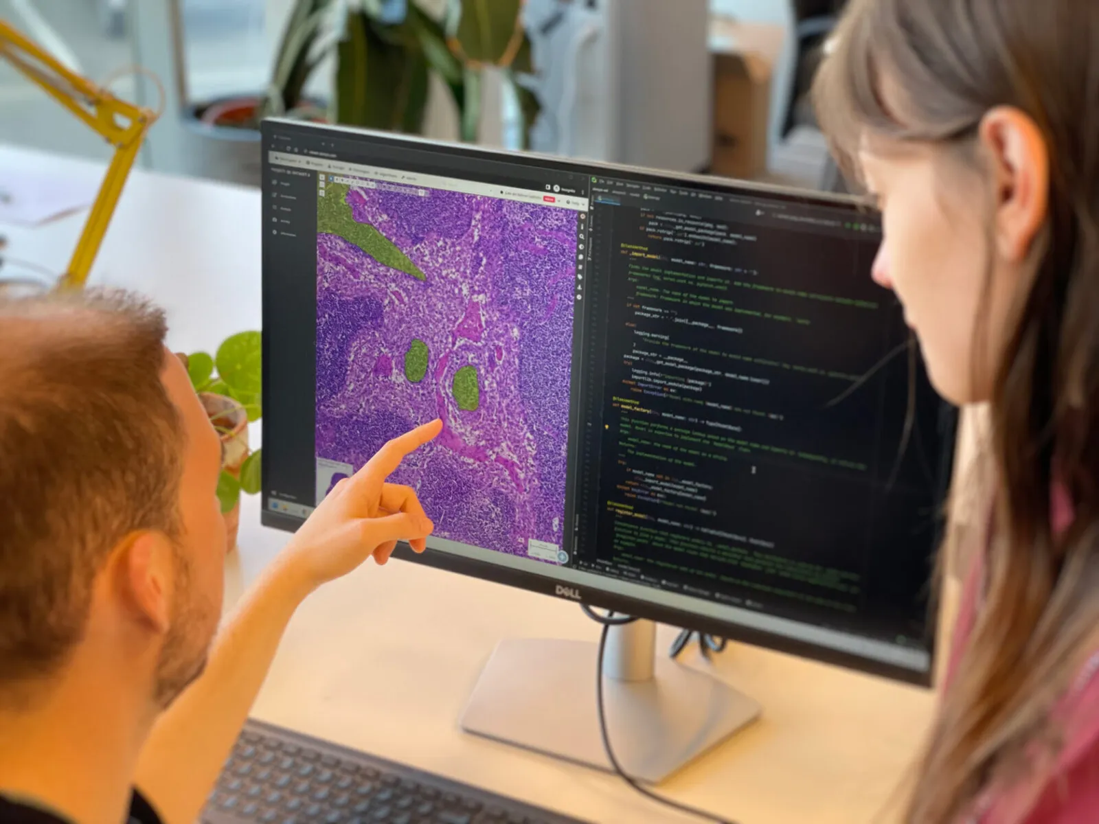 Two Aiosyn colleagues at a screen showing a whole-slide image with the model's detections beside the code that produced them.